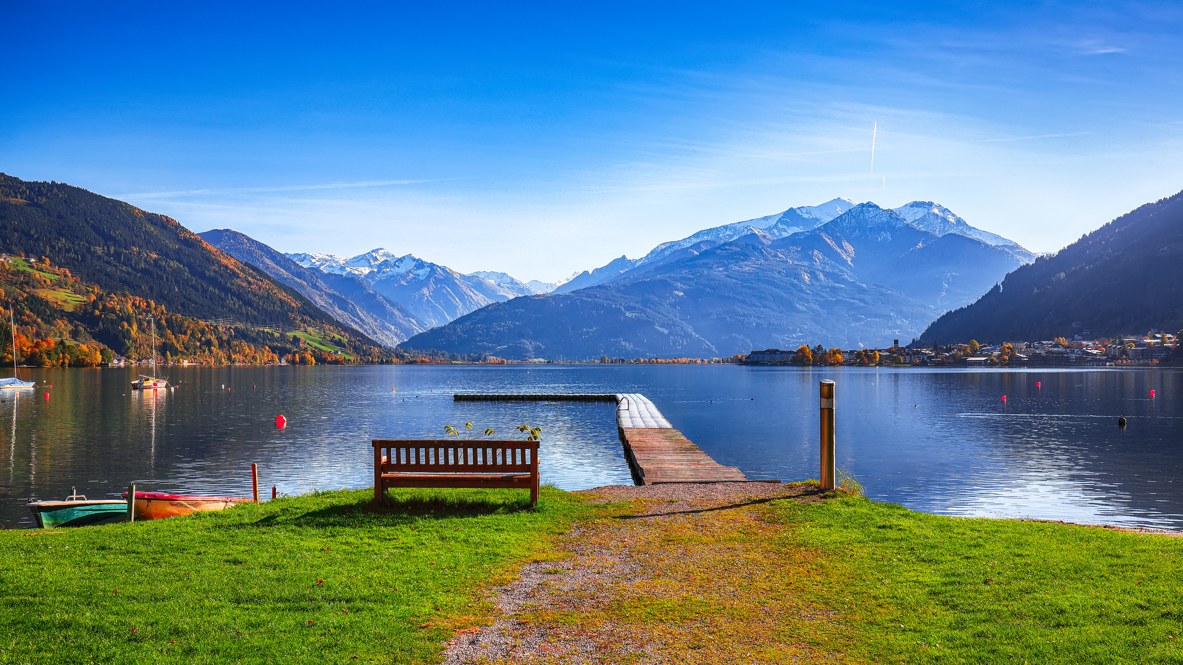 Spektakuläre Herbstansicht des Sees und der Bäume im Stadtpark von Sell Am See. Fantastischer Sonnentag über dem See. "nLocation: Zell am See, Salzburger Land, Österreich, Europa